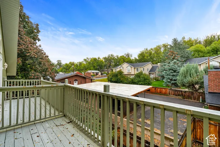 Elevated wooden deck featuring painted railing, uncovered surface, and surrounding tree canopy