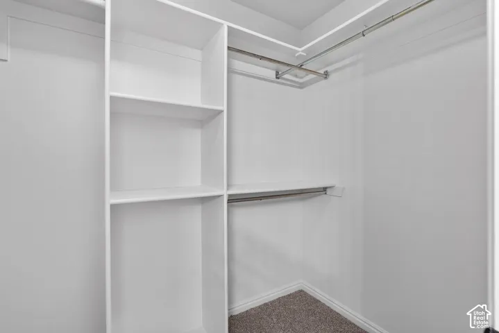 Custom white shelving units featuring built-in vertical storage, open-faced shelving, and metal closet rods