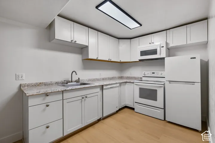 Kitchen featuring white cabinetry, stone-finish countertops, stainless steel sink, built-in dishwasher, and wood-finish flooring