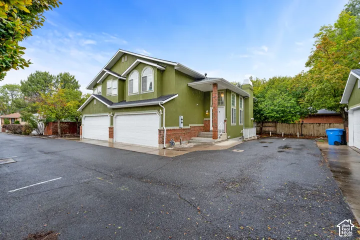 Multi-level exterior featuring stucco and brick siding, dual two-car garages, arched windows, and a covered entryway