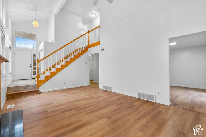 Vaulted ceilings, wood-finish flooring, staircase with natural wood railings, tile entryway, and neutral wall tones