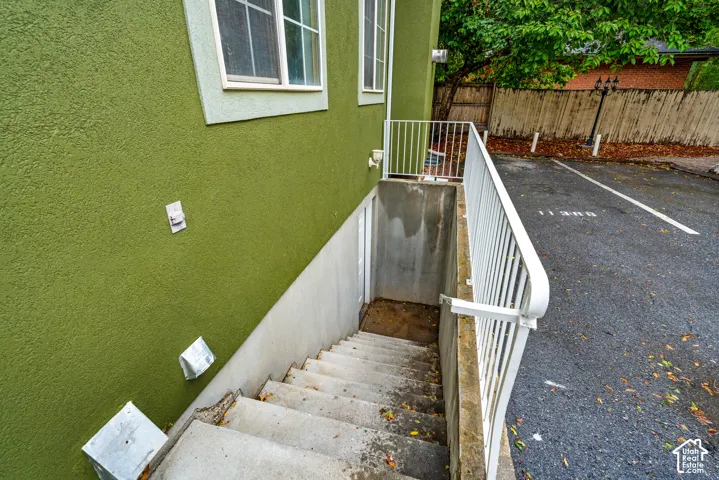Exterior concrete stairwell with white metal railing and paved asphalt parking area