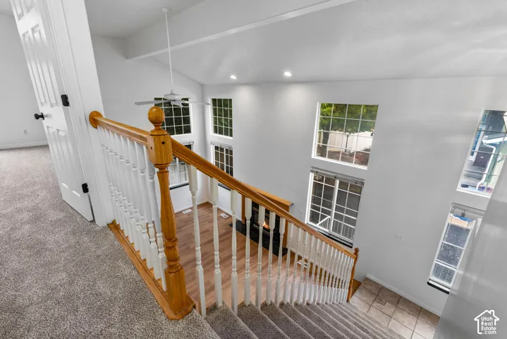 Vaulted ceiling with recessed lighting, multi-level windows, wood-finish flooring, fireplace with a mantle, and a wood-railing staircase