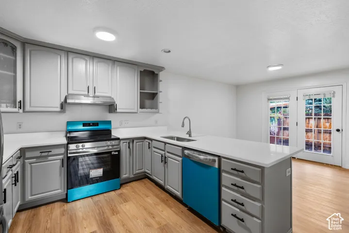 Kitchen featuring gray cabinetry, solid surface countertops, stainless steel appliances, wood-finish flooring, and glass-paneled double doors