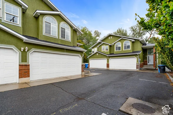 Multi-level exterior featuring stucco siding, brick accents, arched windows, and attached multi-car garages