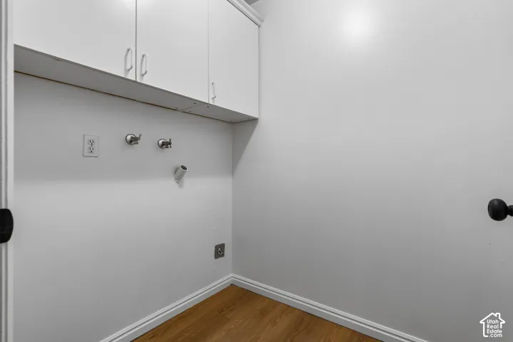 Utility area featuring white built-in upper cabinetry and wood-finish flooring