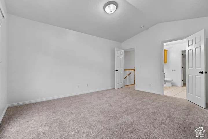 Neutral wall palette, vaulted ceiling, neutral carpeting, and six-panel interior doors