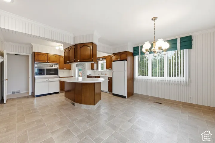 Kitchen featuring wood cabinetry, a central island with white countertop, built-in double ovens, tile flooring, and beadboard wall paneling