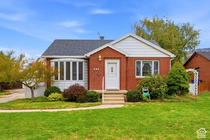 Brick exterior featuring a multi-pane bay window, gable roofline, covered entryway, and concrete steps
