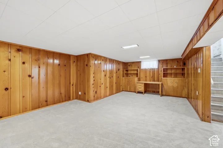 Wood-paneled wall finishes, built-in cabinetry, integrated desk workspace, carpeted flooring, and recessed ceiling lighting
