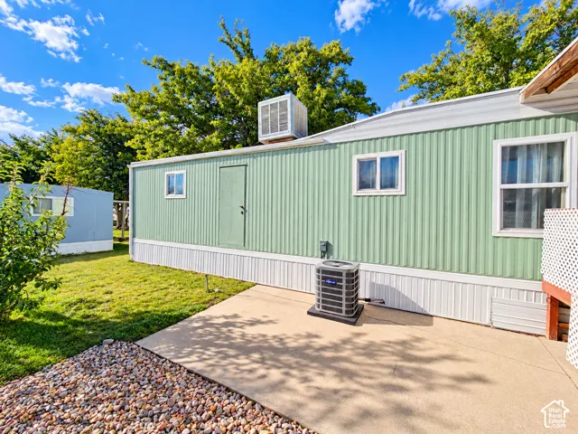 Exterior featuring vertical siding, concrete patio, evaporative cooler, and ground-mounted HVAC unit
