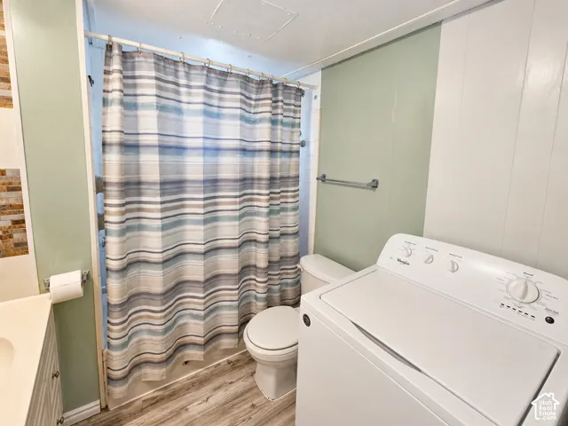 Bathroom featuring a tub-shower combination, wood-finish flooring, wall-mounted towel bar, and vertical paneled wall accents