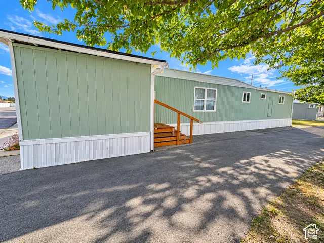 Exterior featuring vertical paneled siding, a paved driveway, and wooden steps with a matching handrail