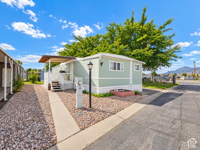 Exterior featuring vertical siding, covered porch, gravel landscaping, exterior lighting fixture, and paved driveway
