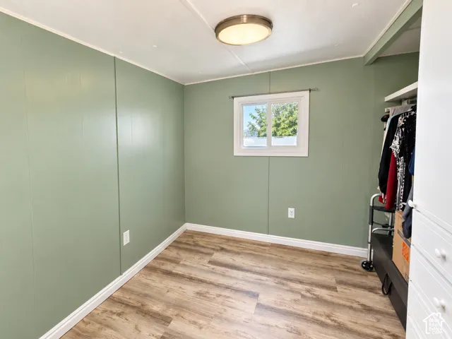 Interior space featuring wood-finish flooring, soft green walls, a white-framed slider window, a ceiling-mounted light fixture, and built-in closet storage