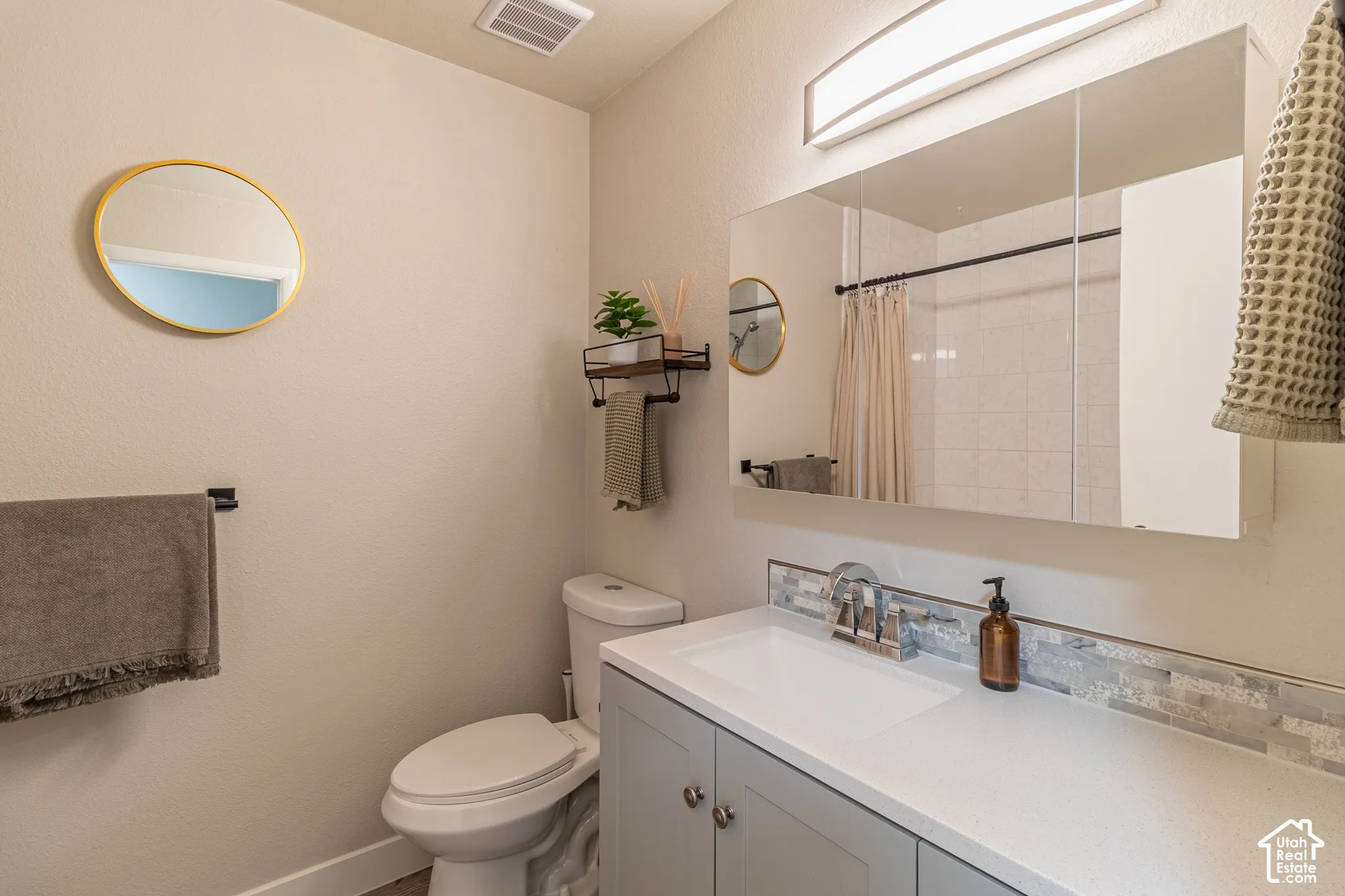 Vanity with an integrated sink, polished chrome faucet, gray cabinetry, and white countertop, complemented by a tiled backsplash