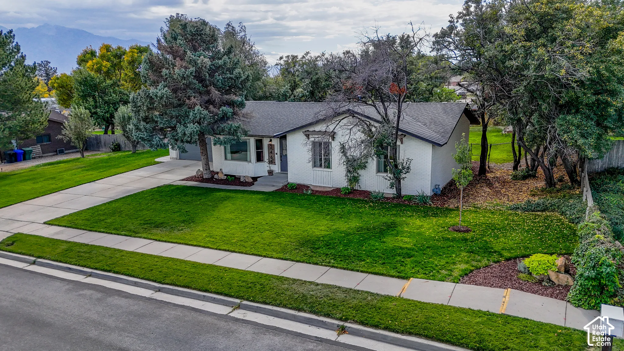 White exterior with dark roof, featuring a well-maintained front lawn