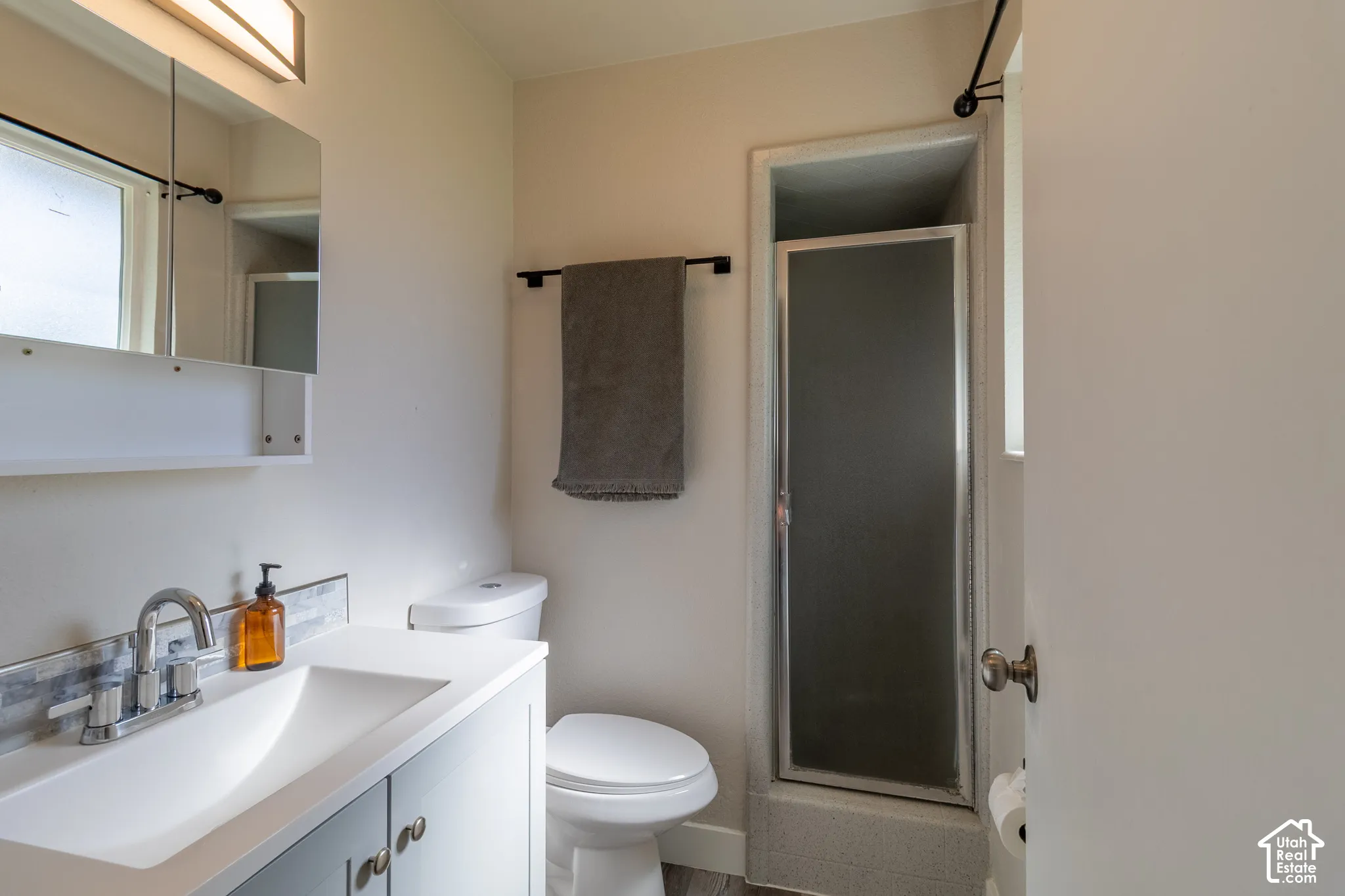 Single vanity with integrated sink, chrome faucet, and tiled backsplash