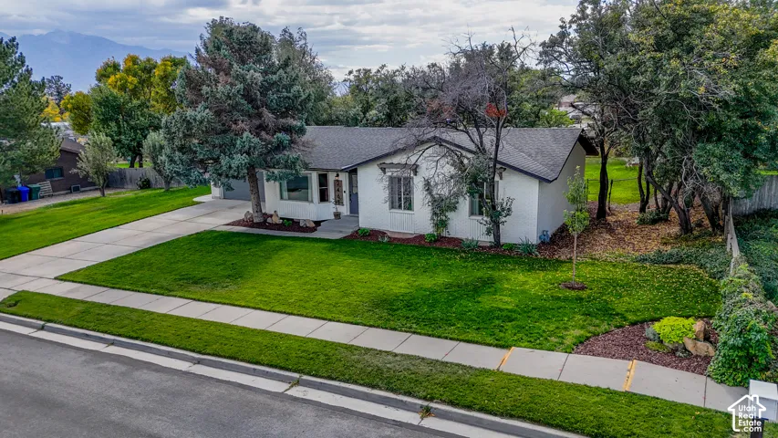White exterior with dark roof, featuring a well-maintained front lawn