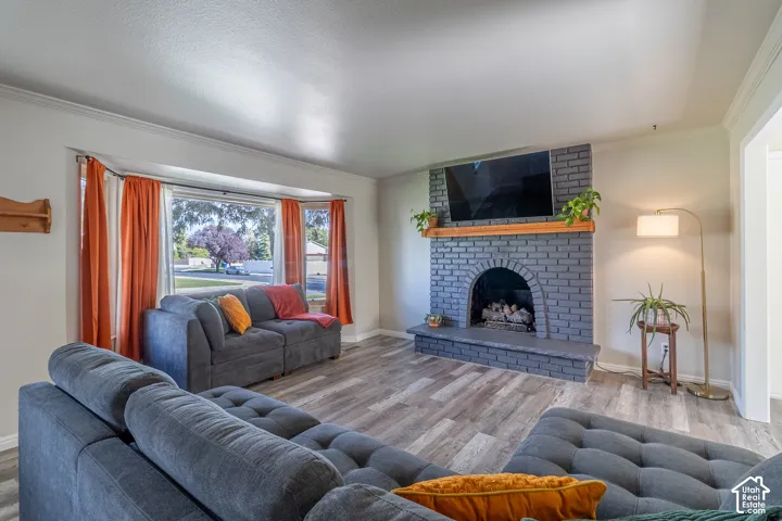 Bay window, painted brick fireplace with wood mantel, wood-finish flooring, and recessed lighting