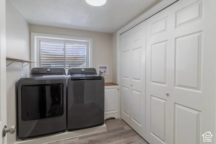 Dedicated laundry area featuring wood-finish flooring, a built-in wood shelf, and white paneled doors