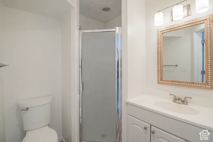 White vanity with an integrated sink and brushed nickel faucet, a decorative framed mirror, and a shower with a clear glass enclosure