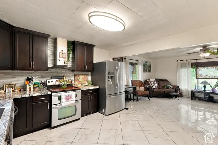 Kitchen featuring dark-finish cabinetry, stone-patterned countertops, a stainless steel range, a chimney-style range hood, and tile flooring