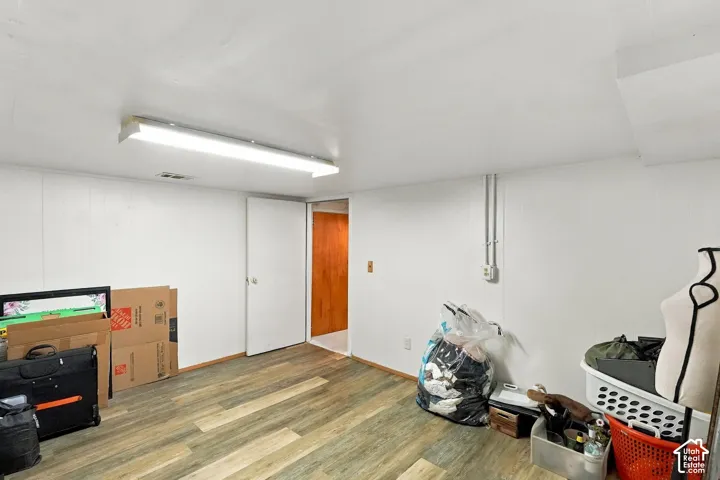 Finished room featuring wood-finish flooring, smooth-finish white walls, and a ceiling-mounted linear light fixture