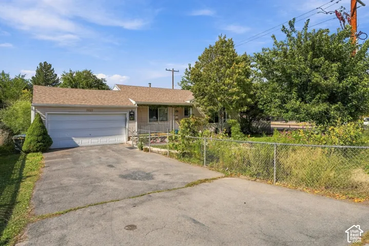 Single-story exterior featuring tan siding, an attached two-car garage, and asphalt driveway
