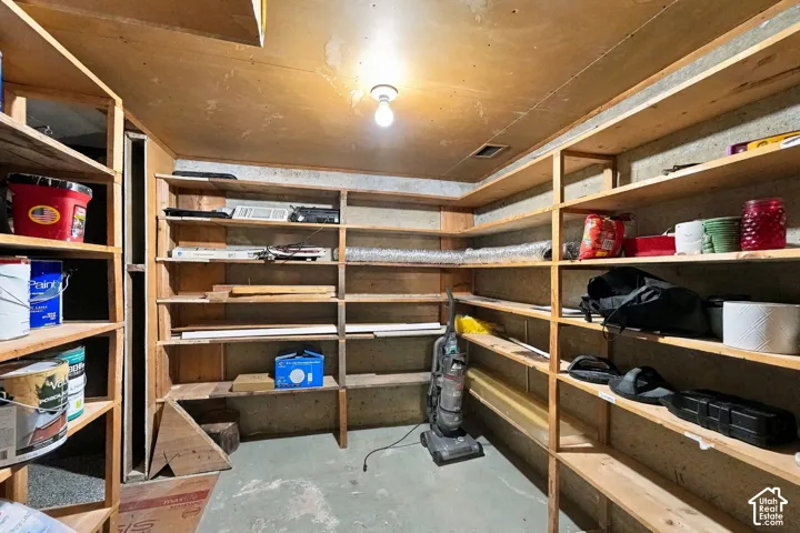 Storage room featuring extensive built-in wooden shelving units and concrete flooring