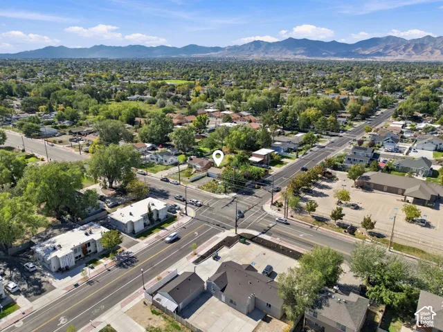 Aerial perspective of the property featuring a prominent mountain backdrop, mature trees, and established infrastructure