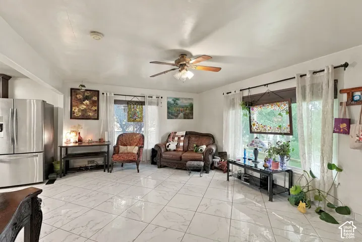 Large-format tile flooring, stainless steel refrigerator, and ceiling fan with integrated lighting