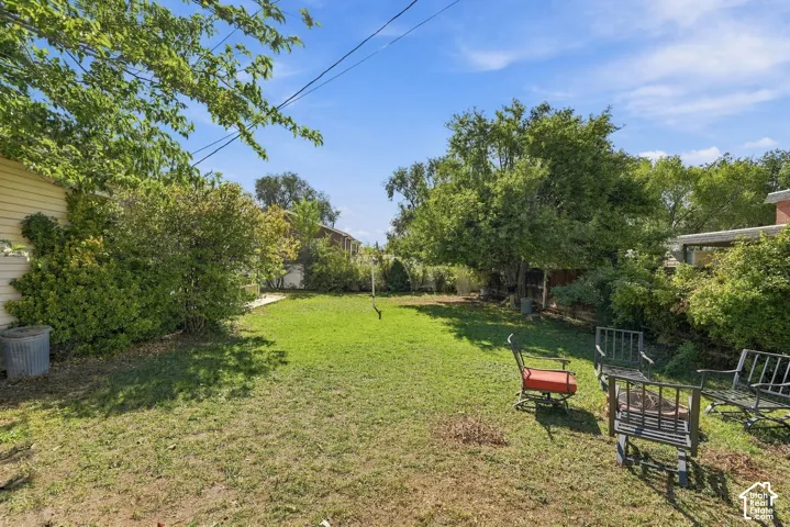 Backyard featuring a grass lawn, mature trees, and perimeter shrubbery