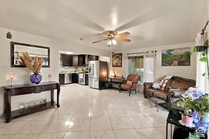 Large-format polished tile flooring, dark-finish cabinetry, stainless steel kitchen appliances, and ceiling fan fixture
