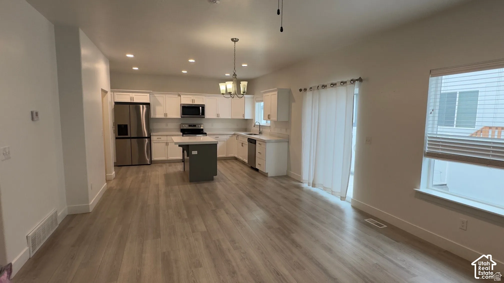 Open-concept floorplan with wood-finish flooring, recessed lighting, and a kitchen island