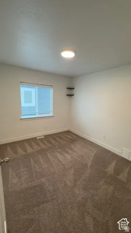 Neutral tone wall paint with white trim, brown patterned carpeting, window with blinds, and ceiling-mounted flush light fixture
