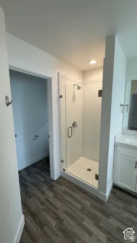 Glass-enclosed shower with a white base, chrome fixtures, and recessed lighting