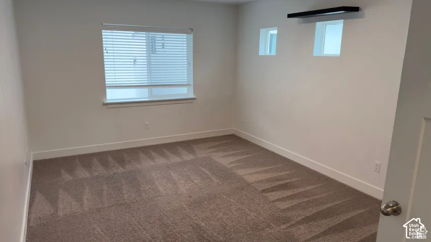 Neutral-toned carpeting, white walls, and a window with blinds