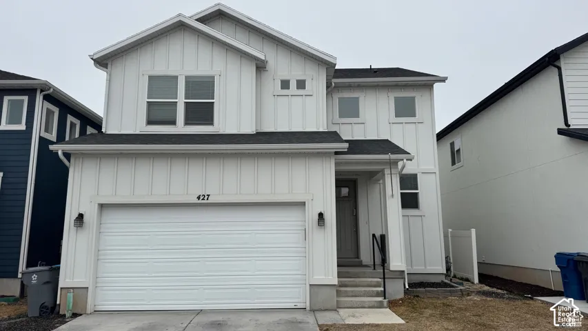 Modern exterior featuring vertical siding, a two-car garage, and a covered entry