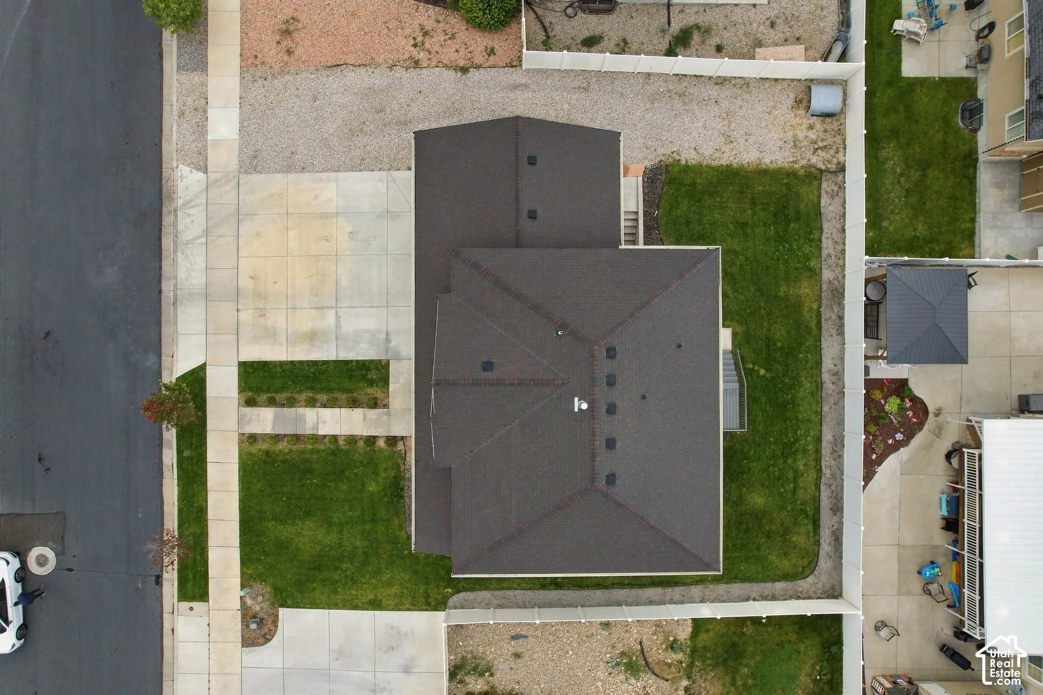 Aerial perspective featuring a multi-faceted roofline, concrete driveway, paved sidewalk, and enclosed yard with lawn area