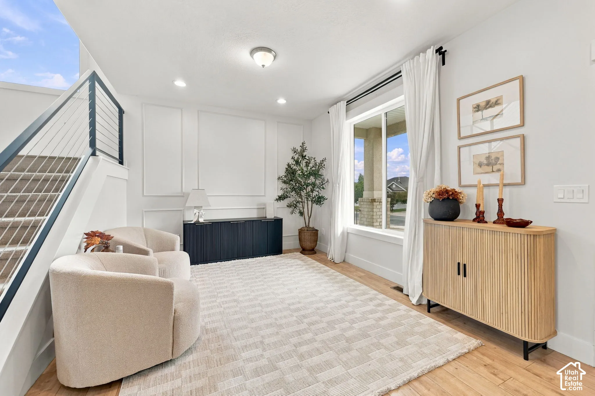 Wainscoting wall paneling, wood-finish flooring, and a staircase featuring a dark-finish metal handrail with cable railing system