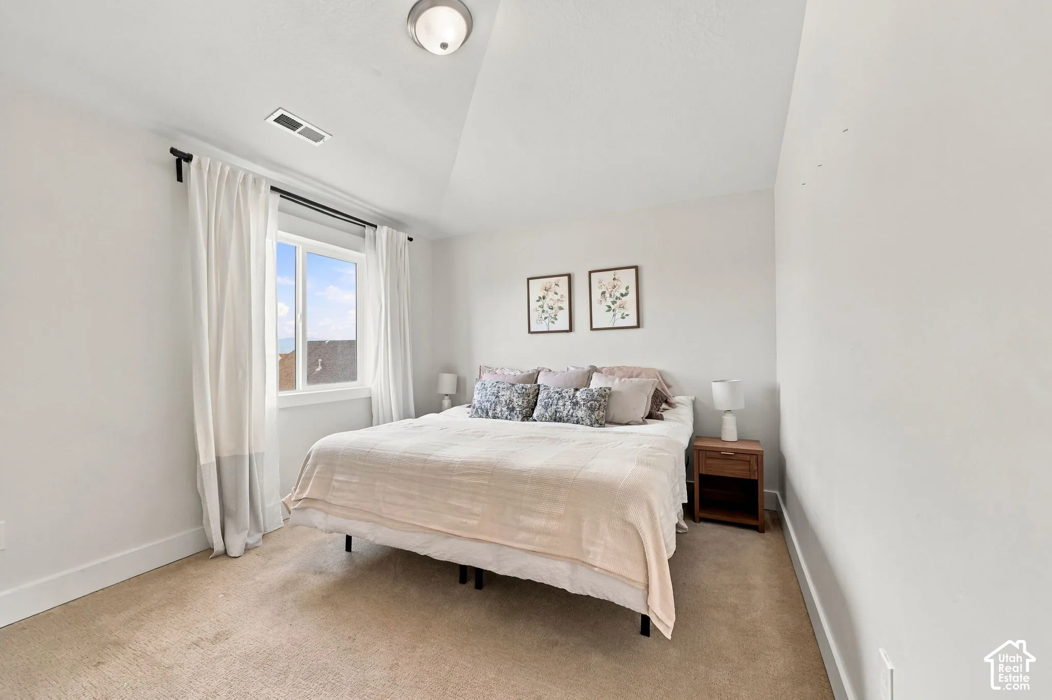 Vaulted ceiling featuring a central flush-mount light fixture and a single window with a white frame