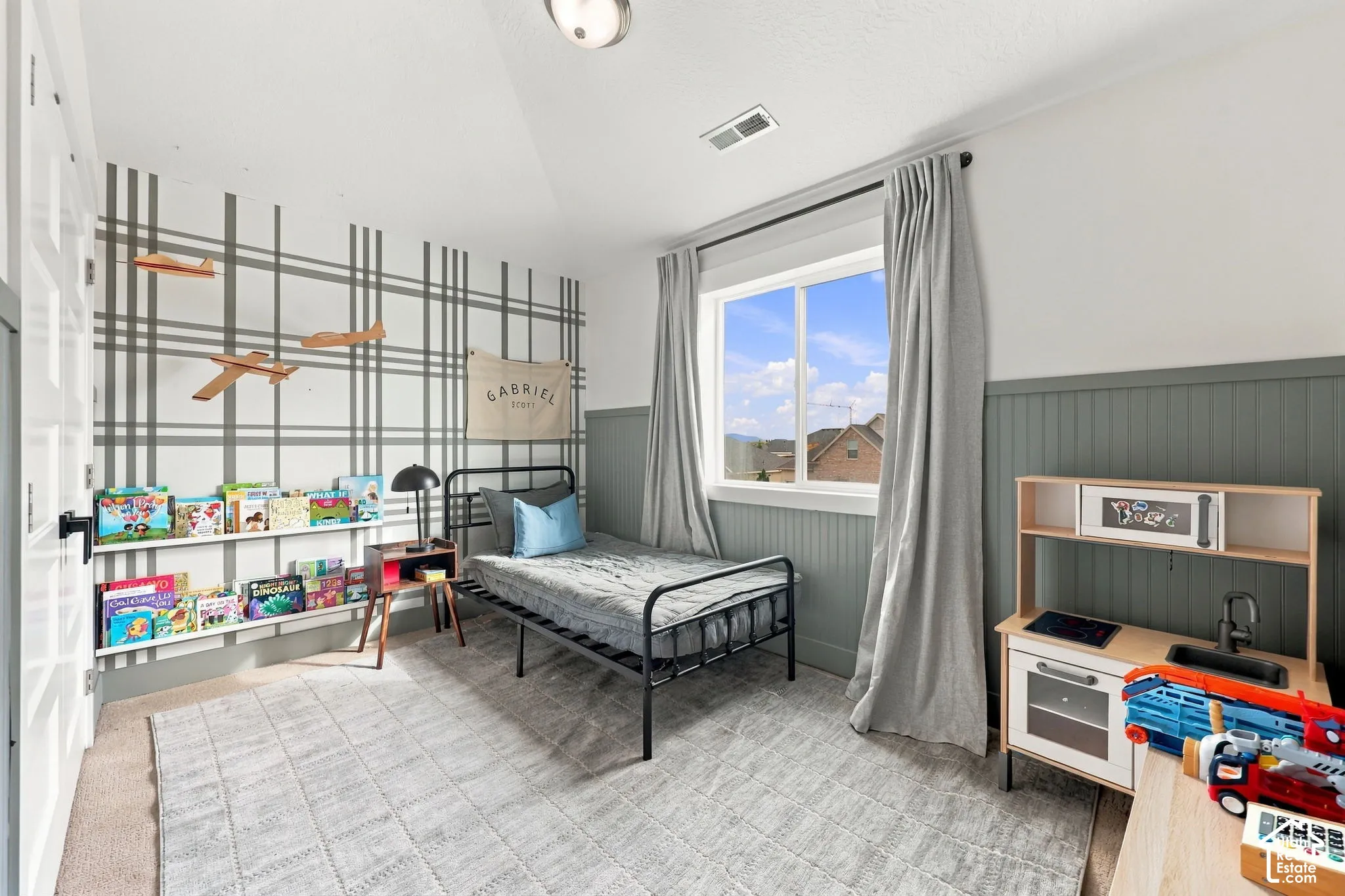 Room featuring vaulted ceilings, floor-to-ceiling wainscoting, a wall-mounted floating display shelf, and a large sliding window with mountain scenery