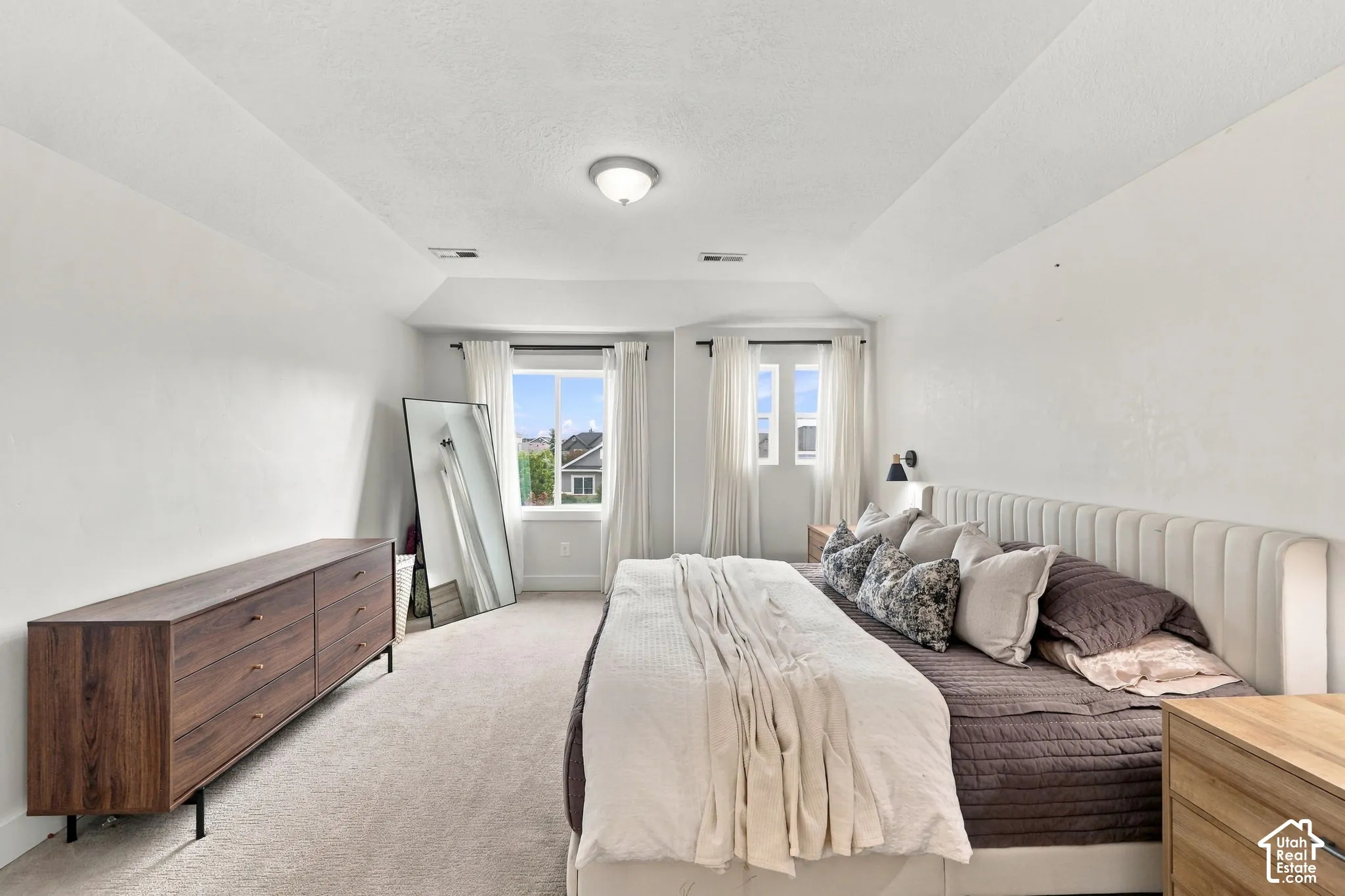 Bedroom featuring a tray ceiling, wall-to-wall carpeting, and dual window placements