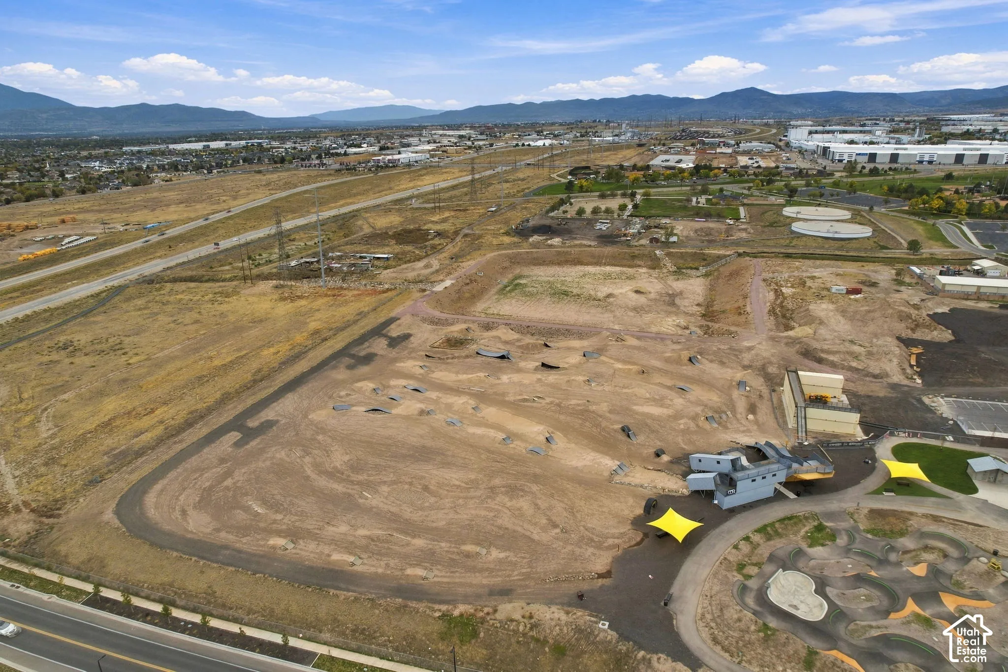Expansive land parcel featuring an established dirt-track course, paved perimeter pathway, and mountain range backdrop