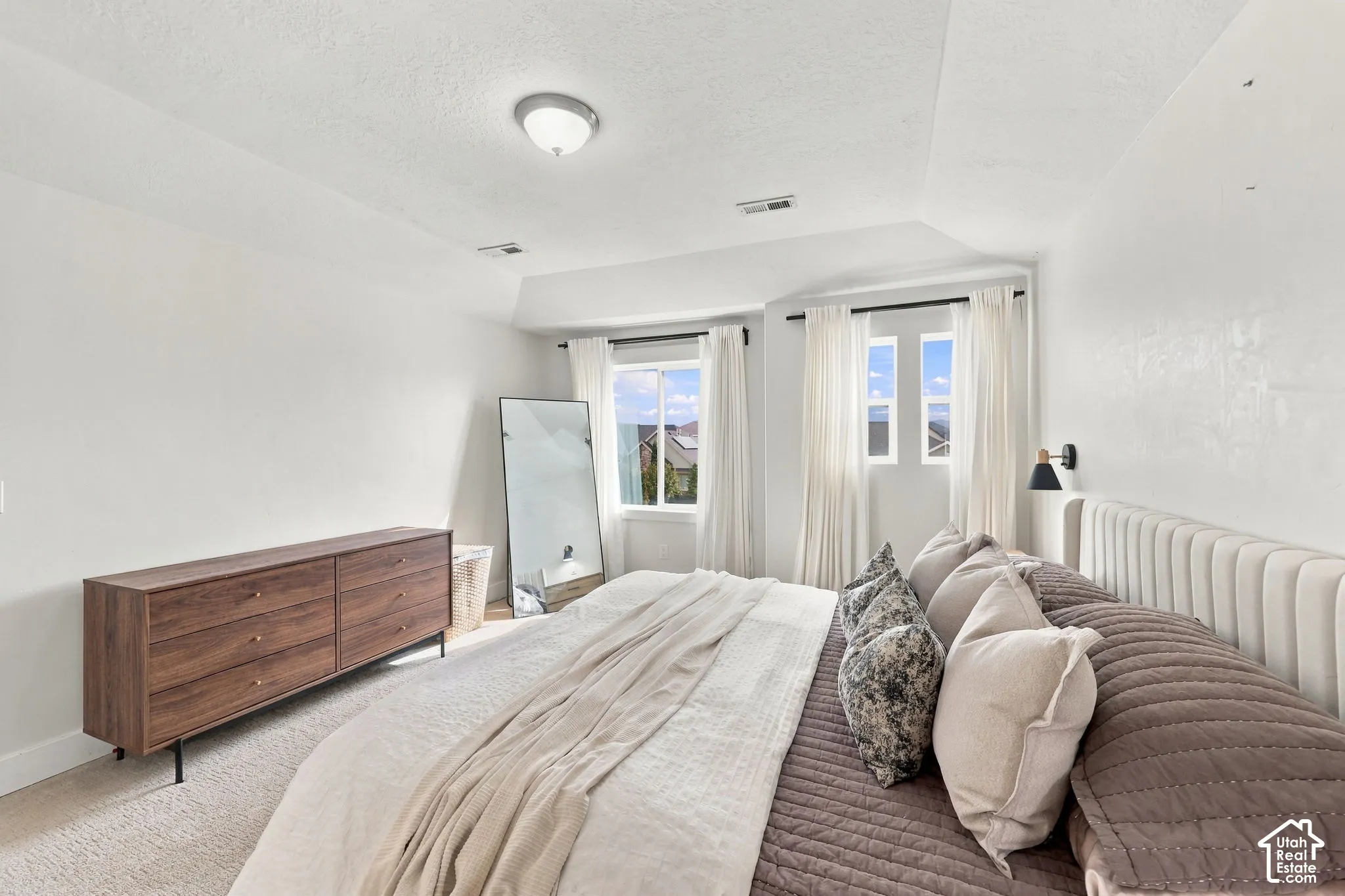 Neutral-toned bedroom featuring a tray ceiling, plush wall-to-wall carpeting, and double-pane sliding windows