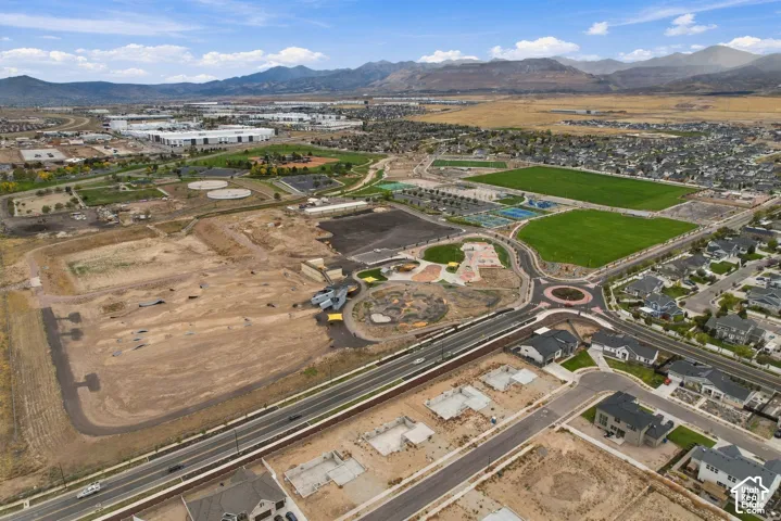 Aerial perspective showcasing residential development with proximity to expansive parkland, multi-use athletic fields, and mountain range backdrop