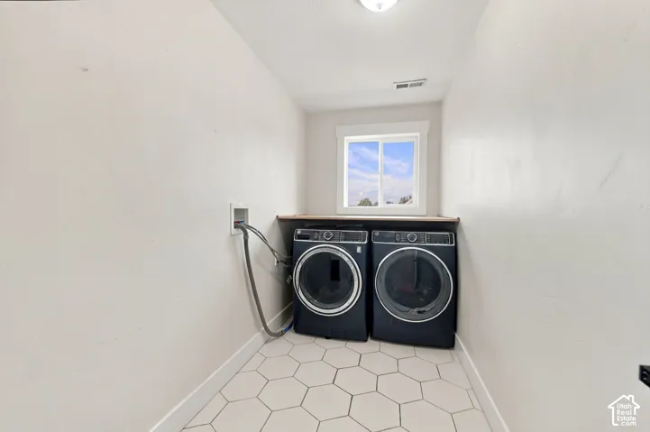 Laundry area featuring hexagon floor tile, built-in wooden folding counter, and a window providing natural light
