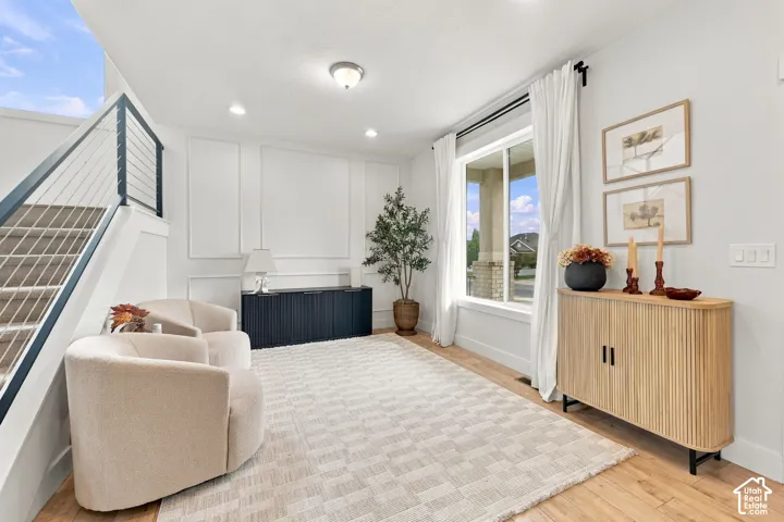 Wainscoting wall paneling, wood-finish flooring, and a staircase featuring a dark-finish metal handrail with cable railing system