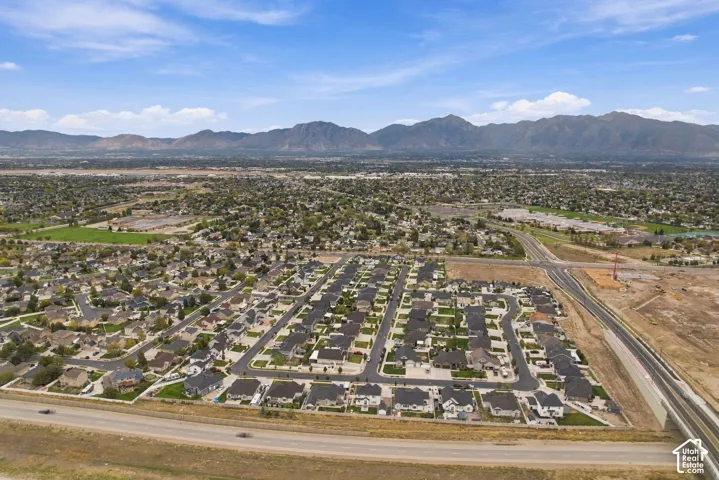Aerial perspective of a suburban residential community featuring paved streets, uniform housing lots, and mountain backdrops